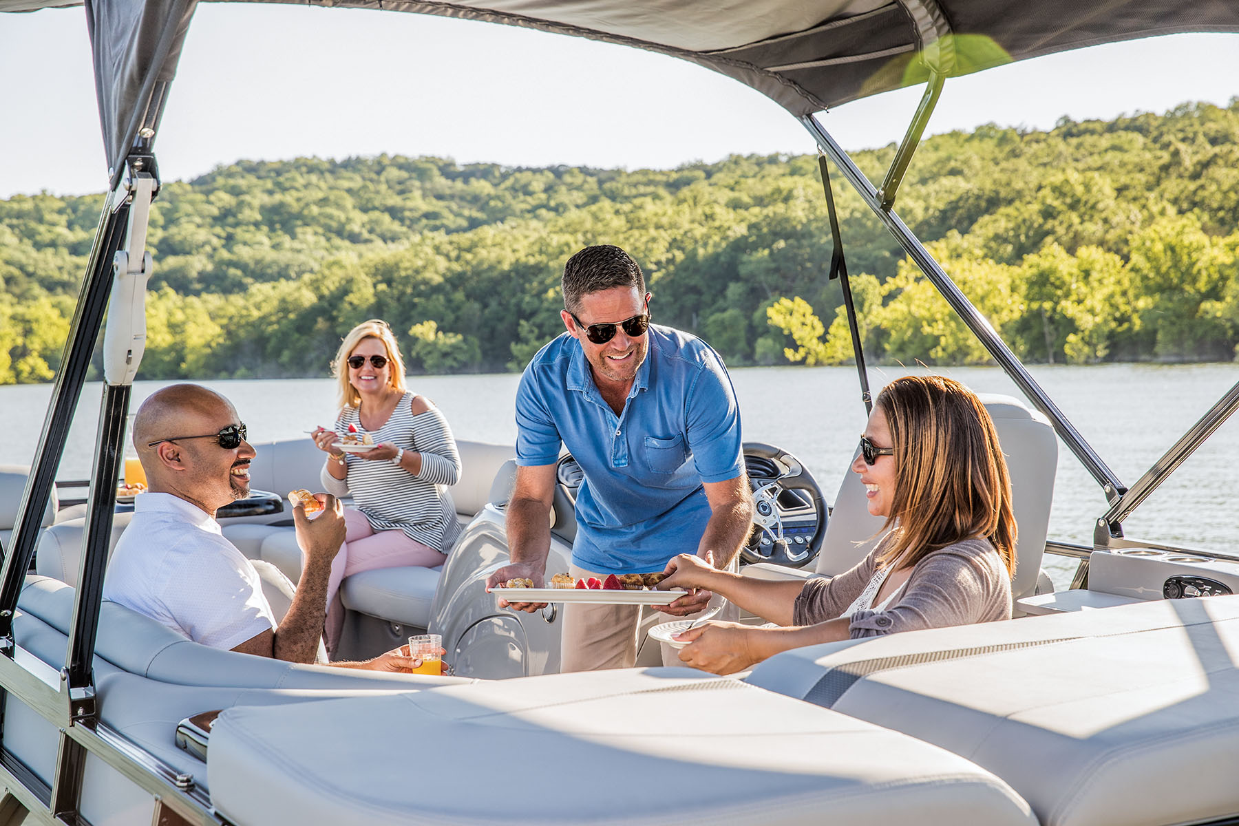 People eating a snack on their pontoon under the lifted Bimini Top